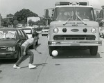 [1970/1979] Boy runs after ball in front of fire engine, c. 1975