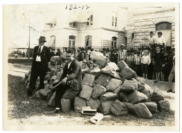 Sheriff Allen Seated on Bags of Confiscated Liquor