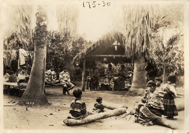 Seminoles Seated in Chickee and by Unlit Fire