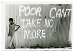 Barefoot child standing in front of graffiti that reads “Poor Can’t Take No More”
