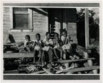 Five children eating sugarcane on a porch