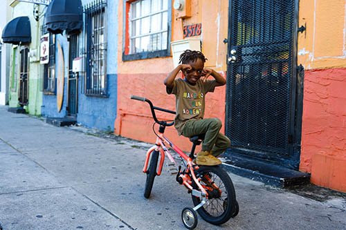 Dandrese Clay Jr., third generation Bahamian, poses with his bike in front of the historical Ike’s Food Center on Douglas Road