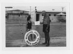 Girl receiving her American Red Cross Swimming Class Certificate from male instructor at the North Miami Municipal Pool