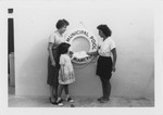 Girl receiving her American Red Cross swimming class certificate from female instructor at the North Miami Municipal Pool