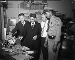 Mayor Sasso and Dade Federal Police officers show money they found stashed in Charles Pretzels tin seized during an operation