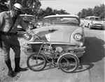 [1957-11-07] Police officer holds a bicycle involved in a car accident