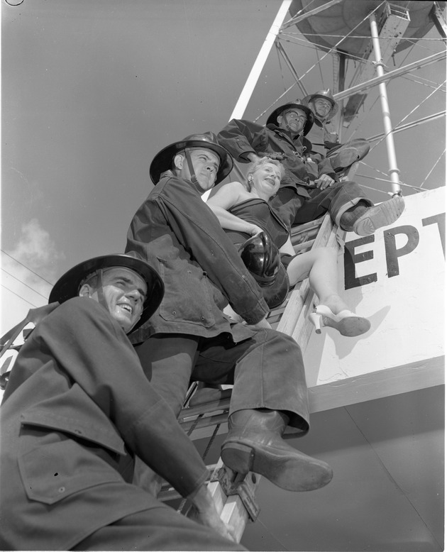 Firefighters and a lady pose on ladder at the North Miami Fire Station