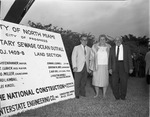 [1965-02-21] Attendees to the Ocean Outfall Groundbreaking ceremony are portrayed by a project site sign
