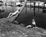 Two young women lying by a canal in Sunny Isles, Florida