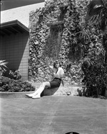 Young girl sitting by a waterfall fountain