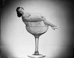 [1959-06-08] Young lady sitting in a large champagne glass