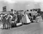 [1954-03-27] Group of children in Native American and clown costumes line up to begin the street parade