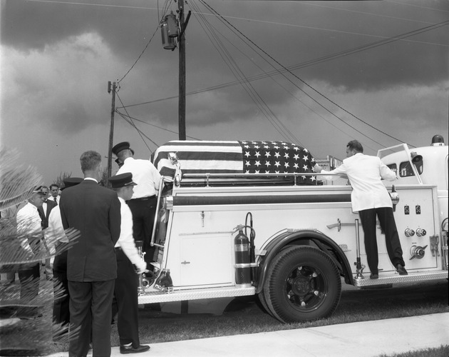 Chief Goyer's flag-draped coffin is placed onto a fire truck for procession to a cemetery