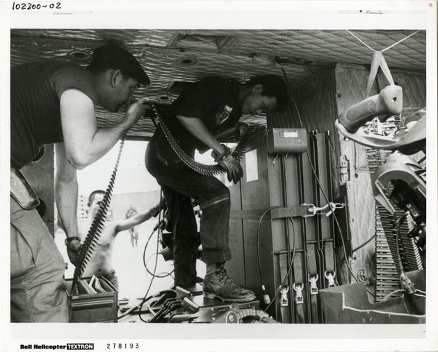 US Army Special Forces soldier and his South Vietnamese counterpart loading Minigun ammunition aboard a UH-1C Gunship helicopter. - 