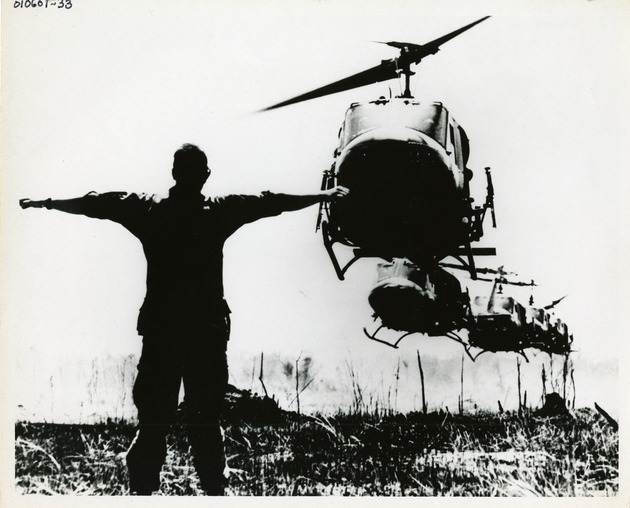 Soldier with outstretched arms watches helicopter landings - 