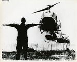 Soldier with outstretched arms watches helicopter landings