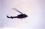 Dark-colored helicopter in flight