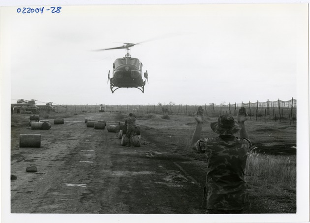 Crew member guides landing helicopter - 