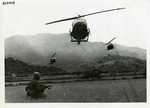 Crouching soldier watches helicopters