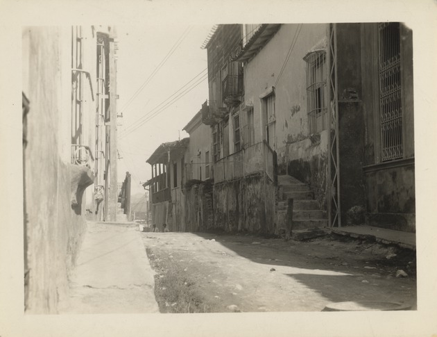 Two men standing on a paved city street, Santiago de Cuba after 1932 earthquake - Recto