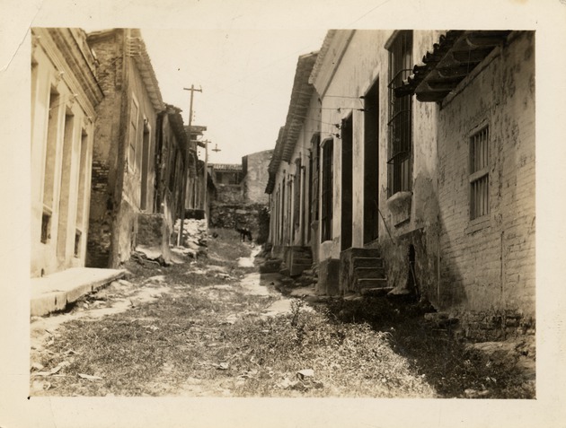 Grass pathway between city buildings in Santiago de Cuba after 1932 earthquake - Recto