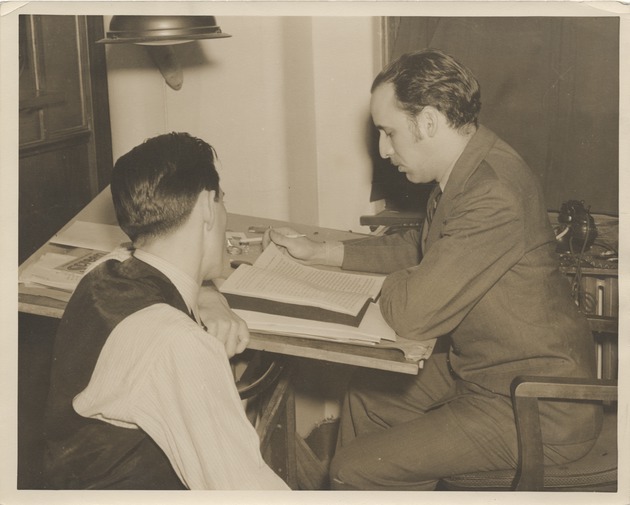 Abril Lamarque (right) sitting at desk with unidentified man - Recto