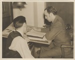 Abril Lamarque (right) sitting at desk with unidentified man