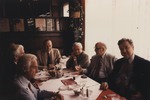 Abril Lamarque holding a glass sitting at a table with a group of men