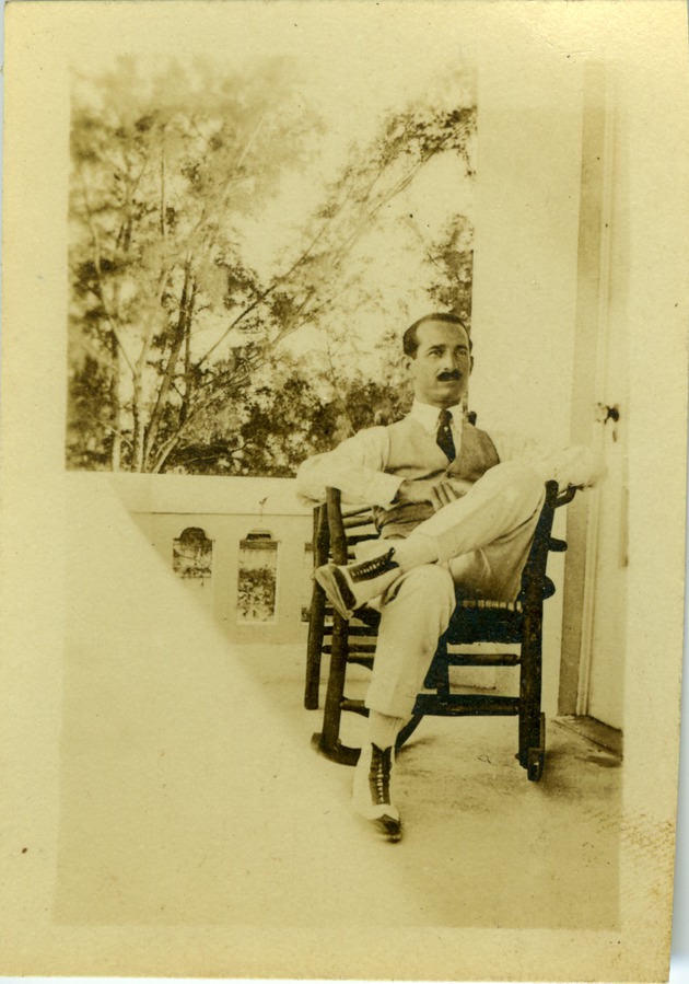 Irwin Cassel  seated in a rocking chair outside - 