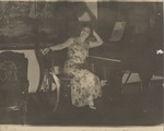Mana-Zucca pictured in a flower print dress seated at a piano