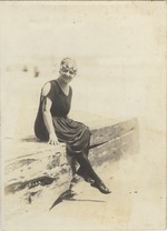Mana-Zucca dressed in a bathing costume seated on a brick wall