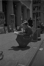 A woman sitting on the sidewalk reading
