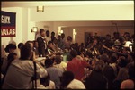 Jean-Bertrand Aristide speaking into a microphone with cameramen