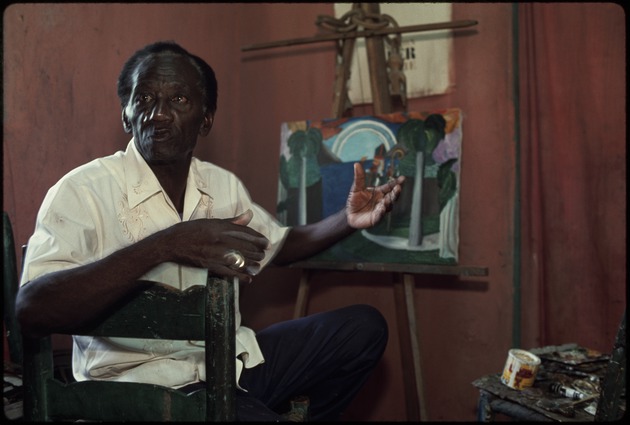 A Haitian painter in front of a painting on an easel