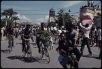 Men on bicycles carrying branches