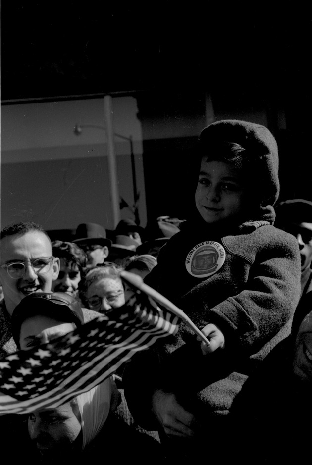Young boy holding American Flag an wearing a Welcome back to earth, Glenn button