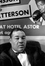 [1960-06] Heavyweight boxer, Joe Louis, sitting in front of Ingemar Johansson and Floyd Patterson fight poster