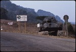 A rusted army tank on the side of the road in front of the sign to the Entrance of the Hotel Selva Negra