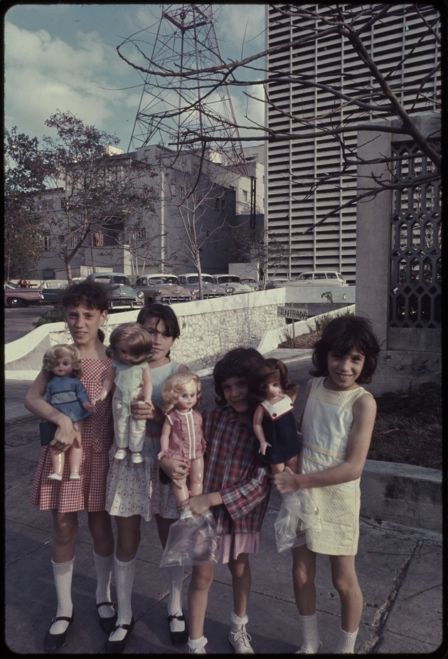 Group of girls with dolls standing in front of a building