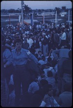 A woman standing over a group of children sitting on the ground at a political rally