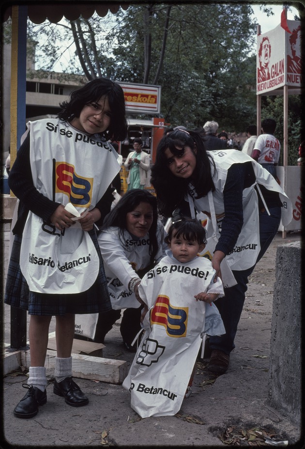 Two women and two children weating Si se puede! Belisario Betancur aprons