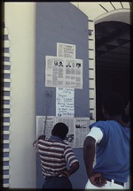 [1990] Two people reading about the candidates for the Haitian presidential election in the newspaper Libete