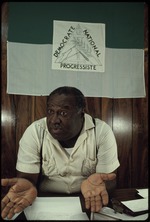 A man sitting in front of the Democrate National Progressiste flag