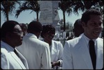 A woman dressed in white talking to two men dressed in white in front of the Jean Jacques Dessalines monument