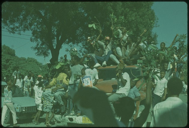 People on a truck with Jean-Bertrand Aristide posters during the 1990 Haitian general election