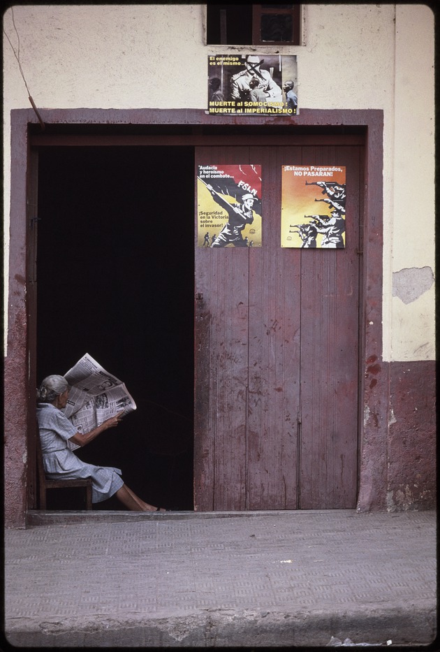 Woman reading the newspaper sitting in an open doorway