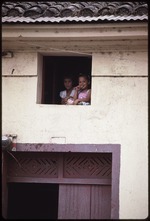Two girls standing at an open window