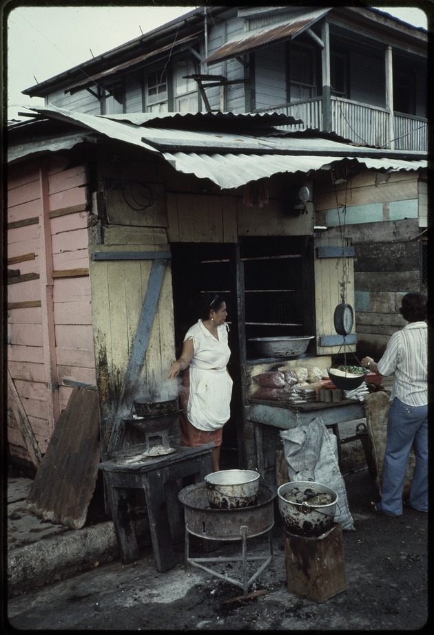 Woman in the doorway of a wooden structure with a scale and food