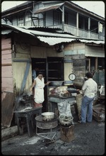 Woman in the doorway of a wooden structure with a scale and food