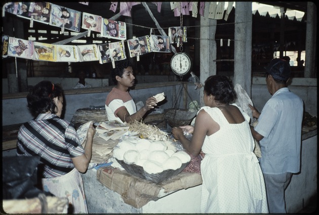 Man conducting business selling vegetables and magazines